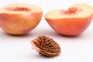 Peach pit with peach in the background. Getty Images